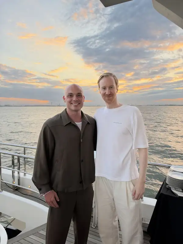 Joachim Haraldsen (til venstre) og Claude Bonde på et båtdekk i solnedgang, med havet bak seg.